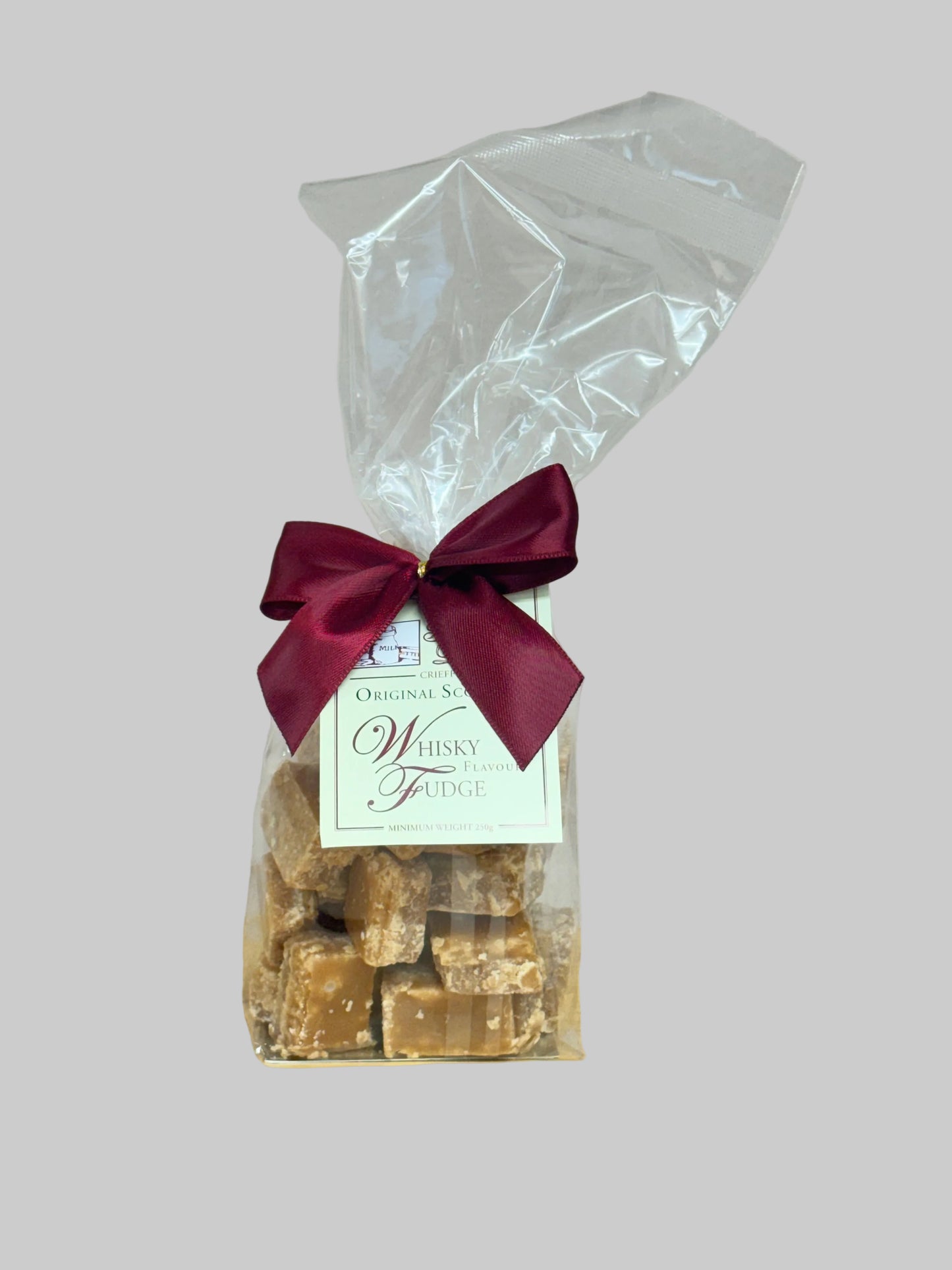 Packaged whisky fudge with a red bow on a light grey background